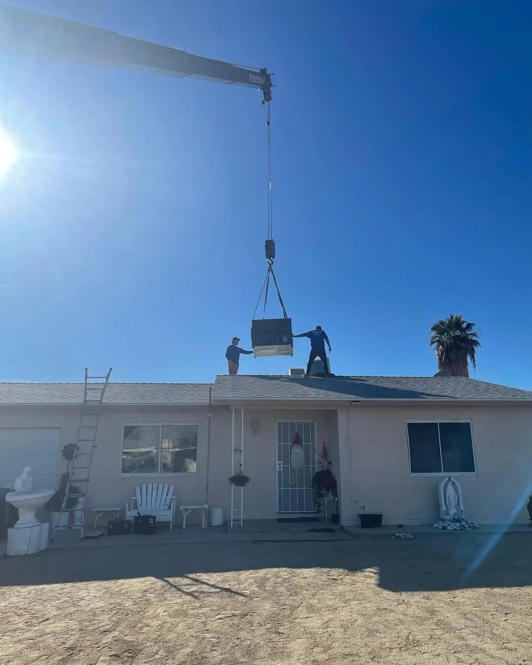 Crane lifting AC unit for rooftop installation